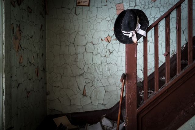 hat and cane in stairwell of abandoned home