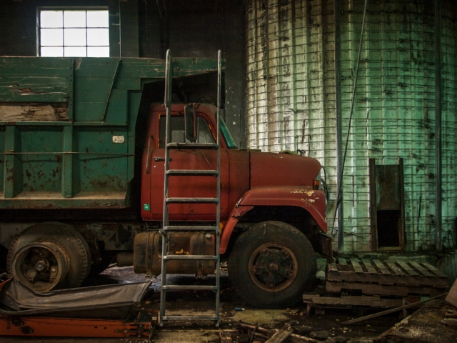 ladder leaning against truck in abandoned greenhouse
